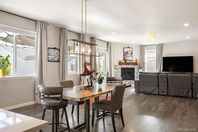 dining area featuring dark wood-type flooring, a wealth of natural light, and a fireplace