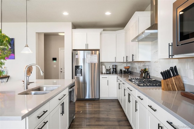 kitchen featuring appliances with stainless steel finishes, wall chimney exhaust hood, white cabinetry, and sink