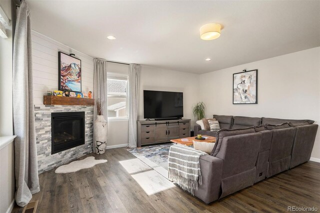 living room with a stone fireplace and dark hardwood / wood-style flooring