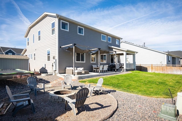 rear view of house featuring a lawn, an outdoor living space with a fire pit, and a patio