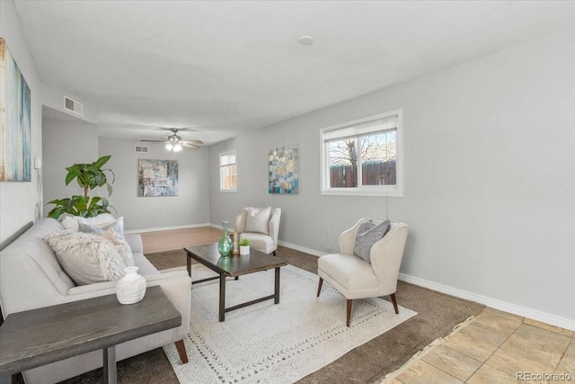 living area featuring a ceiling fan, visible vents, and baseboards