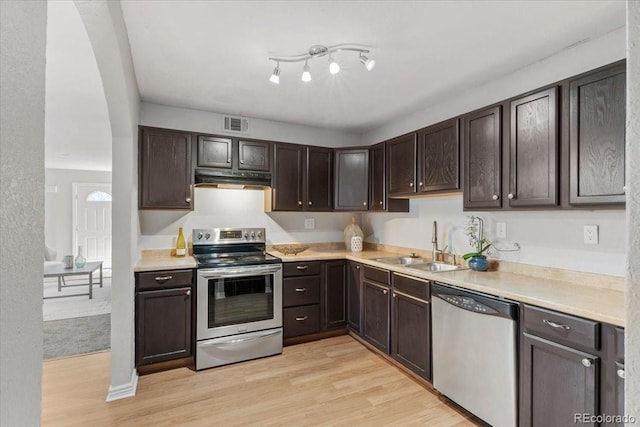 kitchen featuring appliances with stainless steel finishes, light countertops, a sink, and dark brown cabinetry