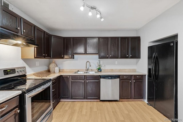 kitchen with light wood finished floors, stainless steel appliances, light countertops, a sink, and under cabinet range hood