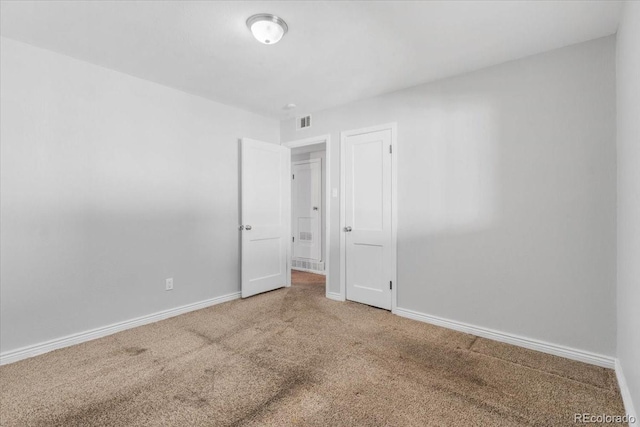 carpeted empty room with visible vents and baseboards