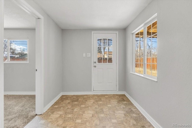 doorway to outside with stone finish flooring and baseboards