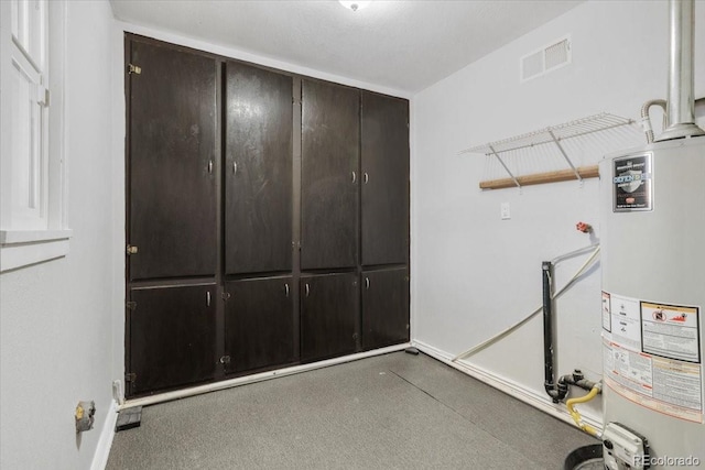 interior space featuring cabinet space, baseboards, water heater, and visible vents