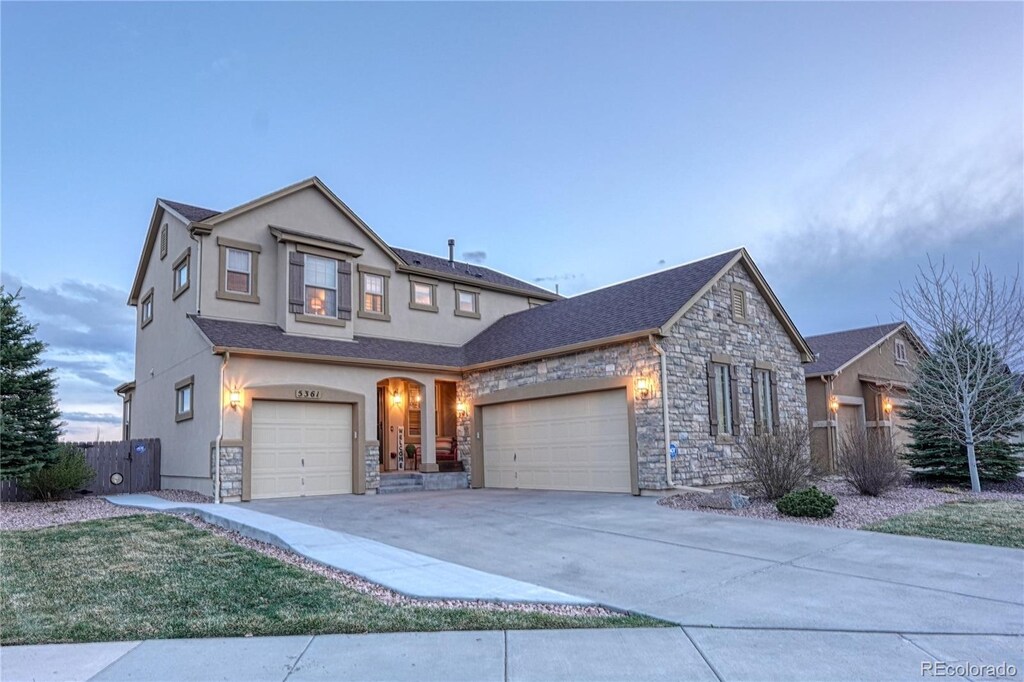5361 Gem Lake Ct, Colorado Springs, CO 80924 - traditional-style home with concrete driveway, stone siding, an attached garage, fence, and stucco siding