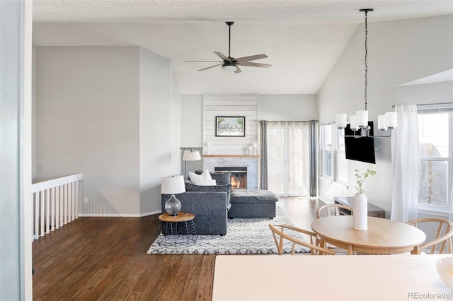 living area with baseboards, a glass covered fireplace, wood finished floors, vaulted ceiling, and a textured ceiling