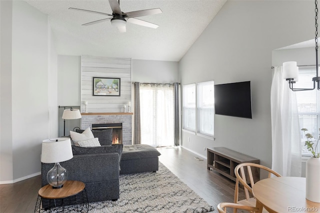 living area featuring lofted ceiling, a fireplace, a textured ceiling, and wood finished floors