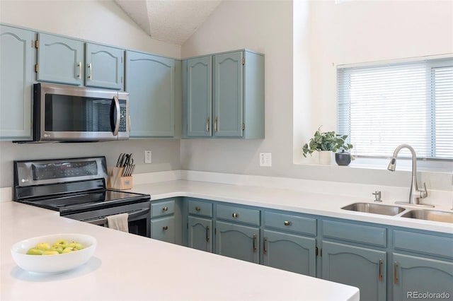 kitchen featuring stainless steel appliances, lofted ceiling, light countertops, a sink, and a textured ceiling