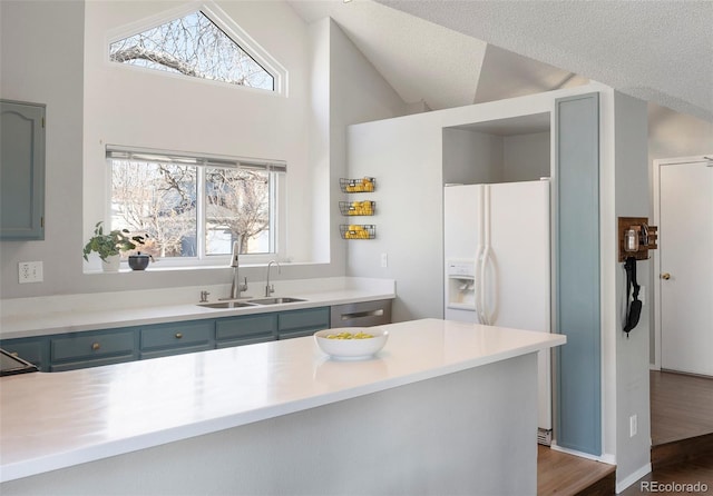 kitchen featuring a textured ceiling, gray cabinetry, a sink, vaulted ceiling, and light countertops