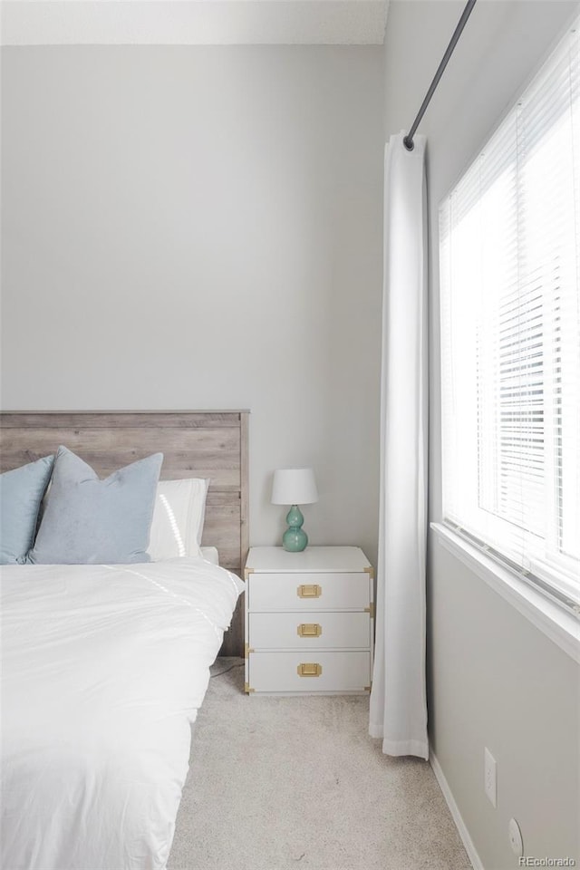 bedroom featuring baseboards and light colored carpet