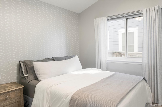 bedroom featuring lofted ceiling, an accent wall, and multiple windows