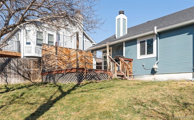 rear view of house with a chimney, a yard, and a deck