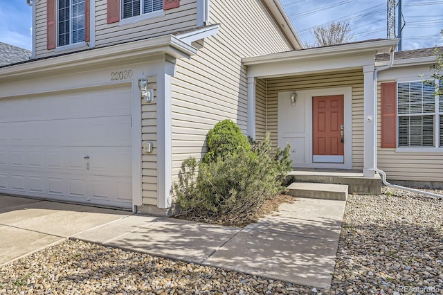 view of exterior entry with a garage and roof with shingles