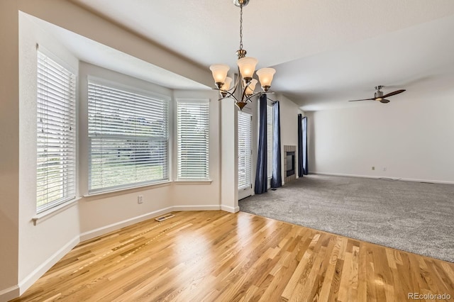 spare room with a chandelier, wood finished floors, baseboards, and a ceiling fan