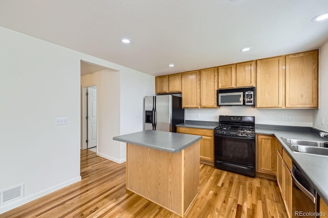 kitchen with appliances with stainless steel finishes, a sink, light wood-style flooring, a center island, and recessed lighting