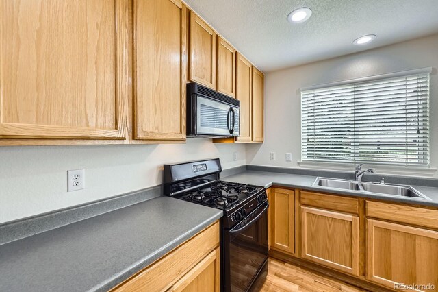 kitchen with black range with gas stovetop, a sink, a textured ceiling, light wood finished floors, and recessed lighting