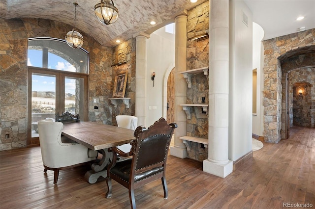 dining room featuring decorative columns, wood-type flooring, and vaulted ceiling