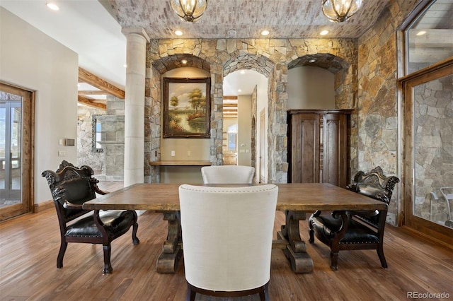 dining room with decorative columns, beam ceiling, and wood-type flooring