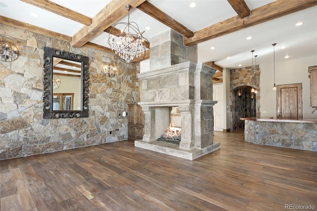 unfurnished living room with a fireplace, an inviting chandelier, beam ceiling, and dark hardwood / wood-style flooring