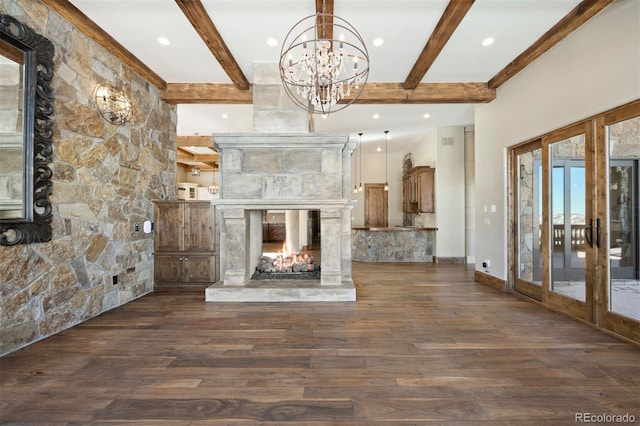 unfurnished living room with beamed ceiling, a stone fireplace, a chandelier, french doors, and dark wood-type flooring