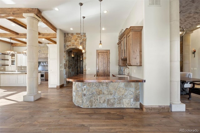 kitchen with decorative columns, hanging light fixtures, and beam ceiling