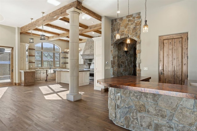 kitchen with decorative columns, a kitchen island, beam ceiling, and premium range hood