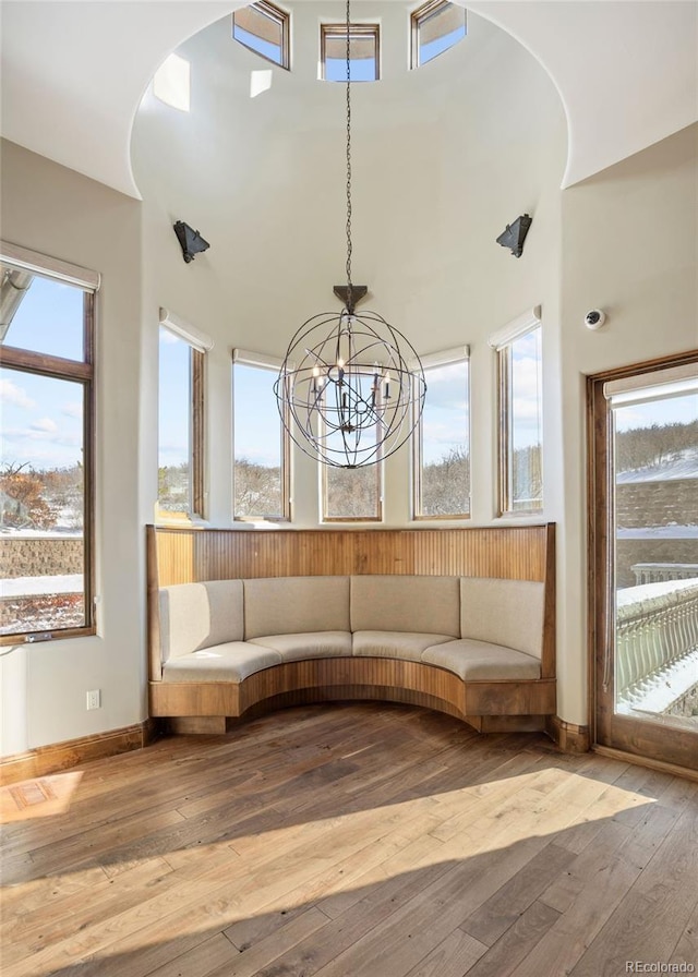 unfurnished room with hardwood / wood-style flooring, a towering ceiling, and a notable chandelier