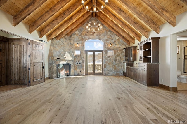 unfurnished living room featuring light wood-type flooring, wooden ceiling, a notable chandelier, and a stone fireplace