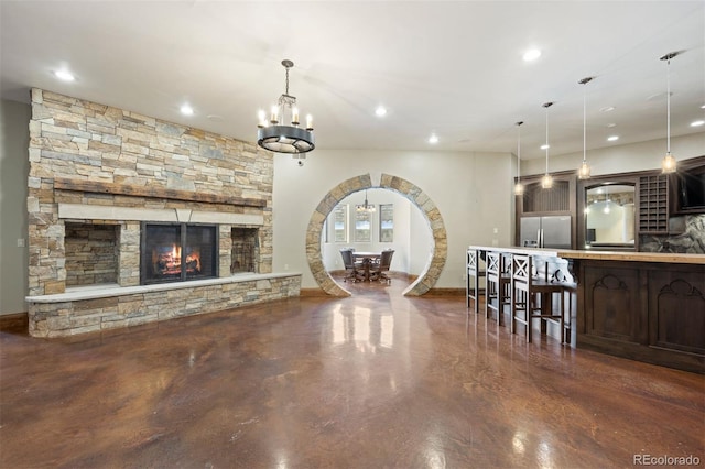 unfurnished living room with a notable chandelier and a stone fireplace