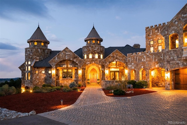 view of front of house featuring stone siding and decorative driveway