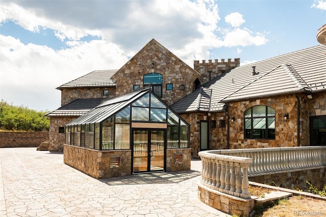 rear view of house with stone siding and french doors