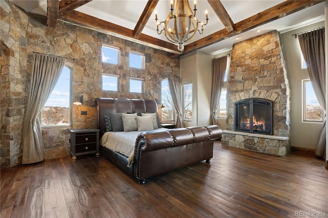 bedroom featuring dark wood-style floors, beam ceiling, multiple windows, and a fireplace