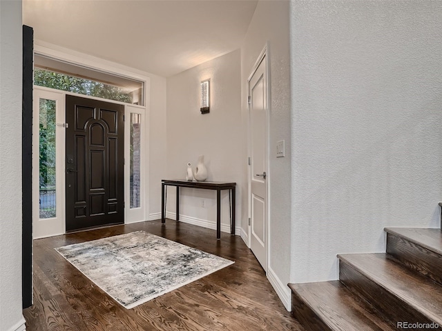 entryway with baseboards, a textured wall, and wood finished floors