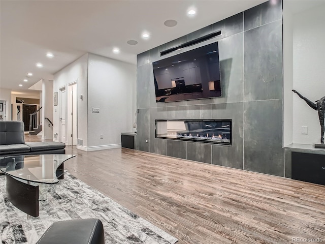 living area with recessed lighting, baseboards, a large fireplace, and wood finished floors