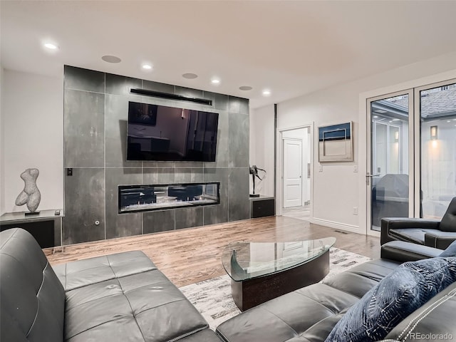 living room featuring baseboards, recessed lighting, wood finished floors, and a large fireplace