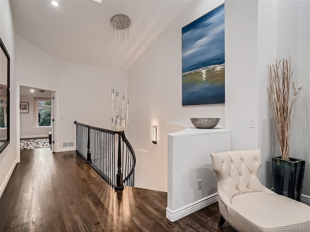 hallway with visible vents, wood finished floors, baseboards, an upstairs landing, and recessed lighting