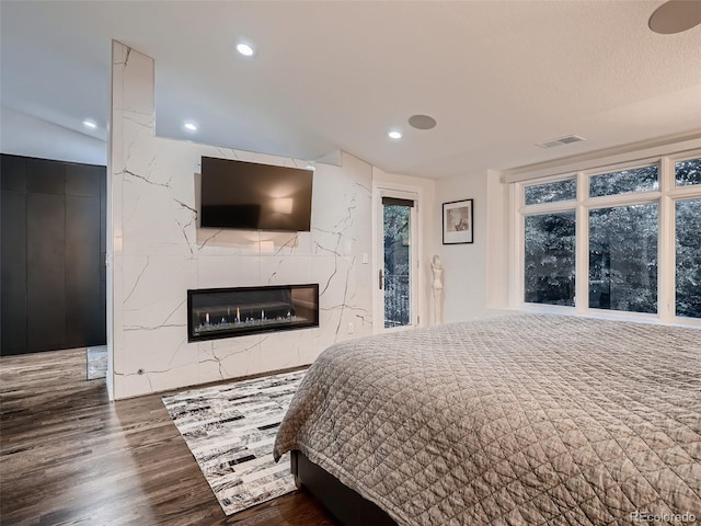bedroom featuring visible vents, recessed lighting, wood finished floors, and a fireplace