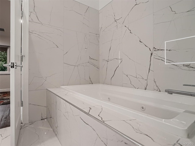 full bath featuring a jetted tub, tile walls, visible vents, and marble finish floor