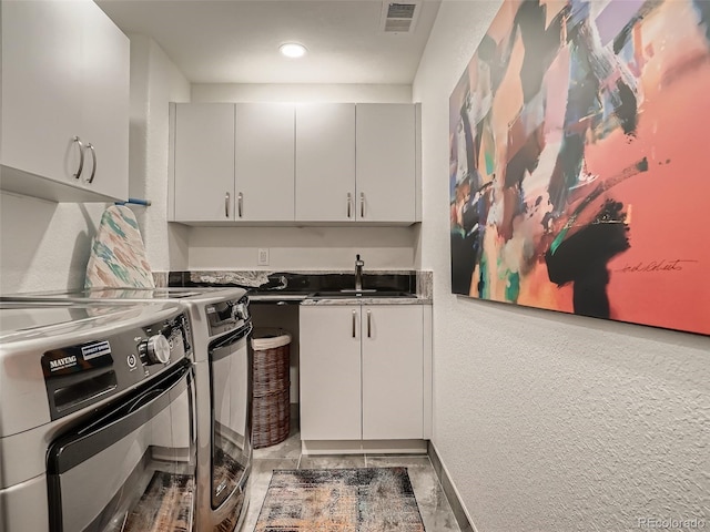kitchen with dark countertops, a sink, separate washer and dryer, baseboards, and visible vents