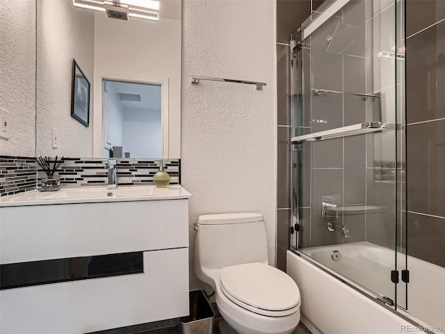bathroom featuring vanity, a textured wall, toilet, tasteful backsplash, and combined bath / shower with glass door