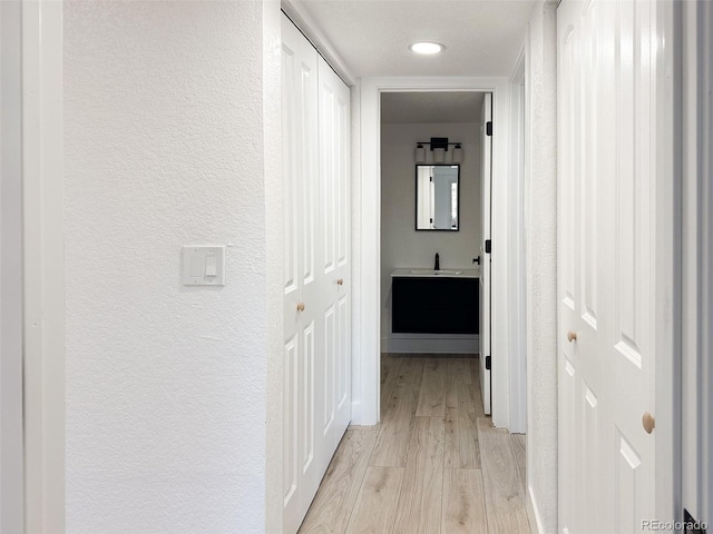 hallway featuring sink and light wood-type flooring