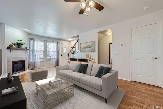 living room with ceiling fan, light wood-type flooring, and a fireplace