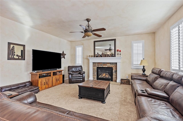 carpeted living room with ceiling fan and a fireplace