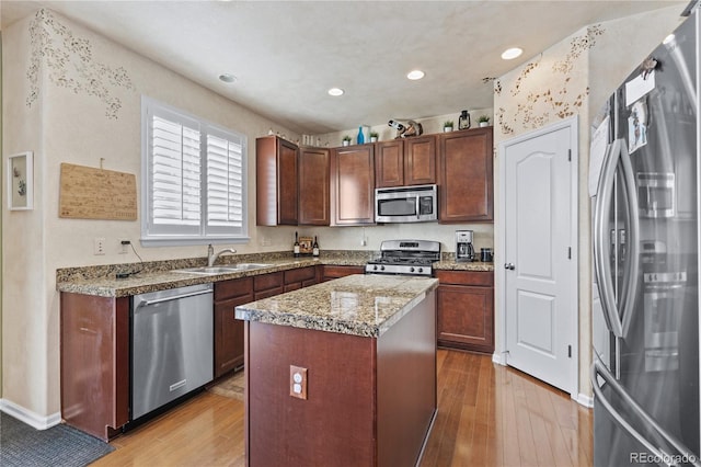 kitchen featuring stainless steel appliances, a kitchen island, sink, and light hardwood / wood-style floors