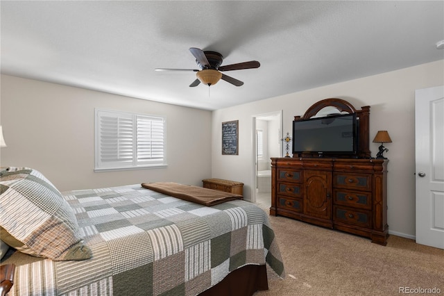 bedroom with ensuite bath, light colored carpet, and ceiling fan