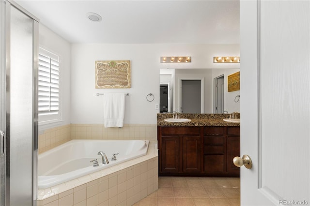 bathroom featuring vanity, tile patterned flooring, and tiled tub