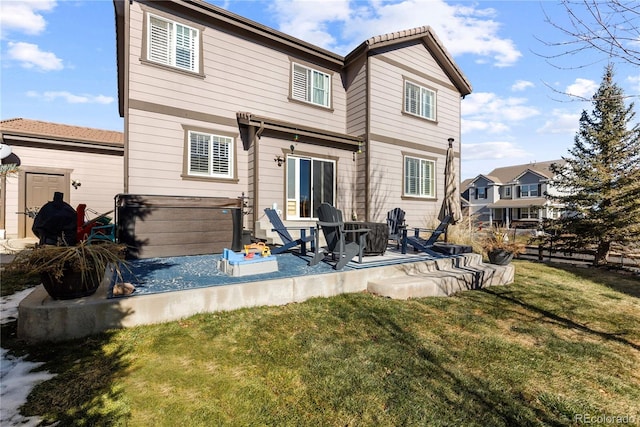 rear view of house featuring a hot tub, a patio area, and a lawn