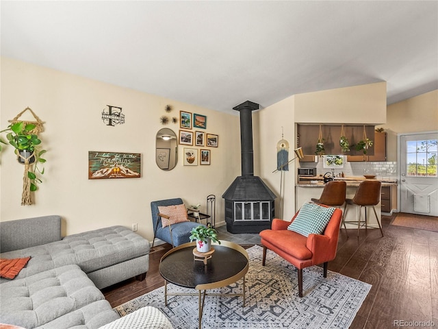 living room featuring a wood stove, dark wood-type flooring, and lofted ceiling